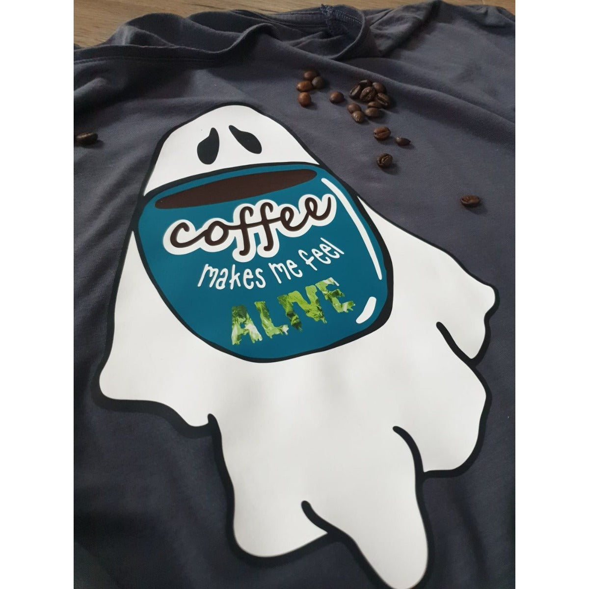 Coffee Ghosts Plotterdatei – großer Geist mit türkiser Tasse und „coffee makes me feel alive“ auf einem dunkelblauen Shirt, dazu Kaffeebohnen