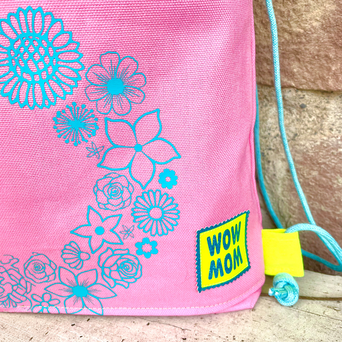 WOW MOM Freebie Plotterdatei – neongelbes Label mit türkisem WOW MOM auf einem pinken Turnbeutel mit türkisen Blumen