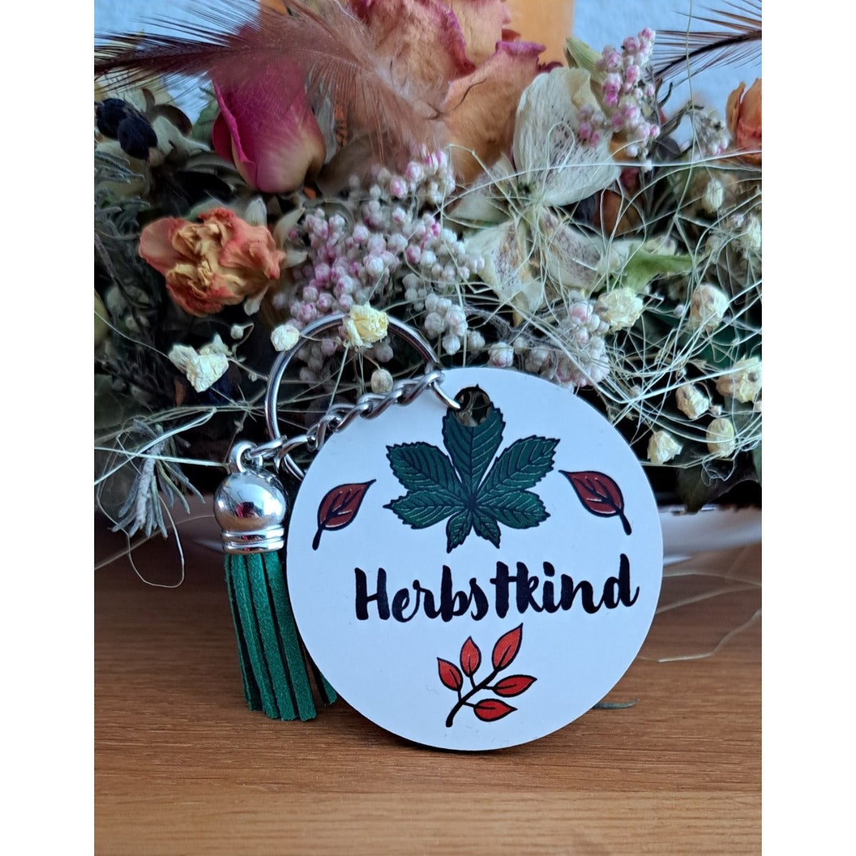 Herbstkind Plotterdatei – Schriftzug mit Kastanienblatt auf einem runden Schlüsselanhänger mit grüner Quaste