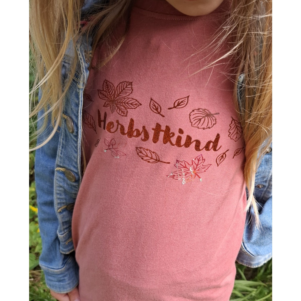 Herbstkind Plotterdatei – rotbrauner Glitzer-Plot mit Blättern auf beerenfarbenem Shirt, dazu eine Jeansjacke