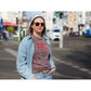 Intolerant Club Plotterdatei – Statement „Too educated for hate“ in Rot auf einem mauvefarbenen Shirt, Frau mit Sonnenbrille und Jeansjacke in der Stadt