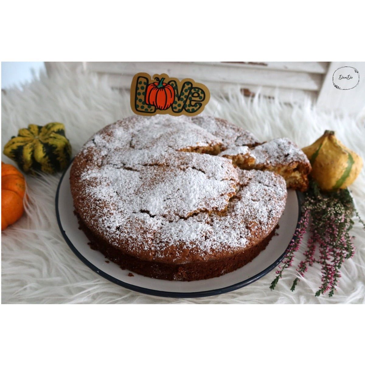 Kürbis Liebe Plotterdatei – Love-Schriftzug mit Kürbis als Caketopper auf einem Kürbiskuchen mit Puderzucker, dekoriert mit Zierkürbissen und Heidekraut