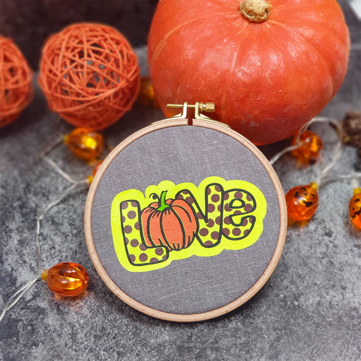 Kürbis Liebe Plotterdatei – Love-Schriftzug mit Punktemuster und neongelbem Offset im runden Stickrahmen, daneben Kürbis und Lichterkette