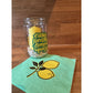 Windlicht aus einem Einmachglas mit dem Schriftzug Easy Peasy Lemon Squeezy in Grün, gelbe Kerze und Serviette mit Zitronenmotiv