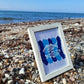 Gerahmtes Bild mit zwei Fischen der Plotterdatei Sea Life auf blauem Hintergrund am Strand