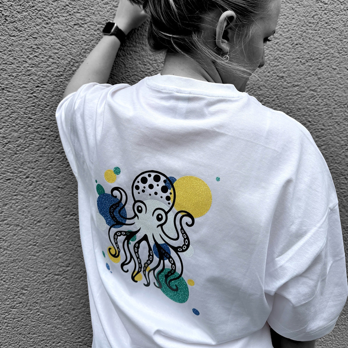 Frau von hinten im weißen T-Shirt mit Kraken der Plotterdatei Sea Life in bunter Glitzerfolie