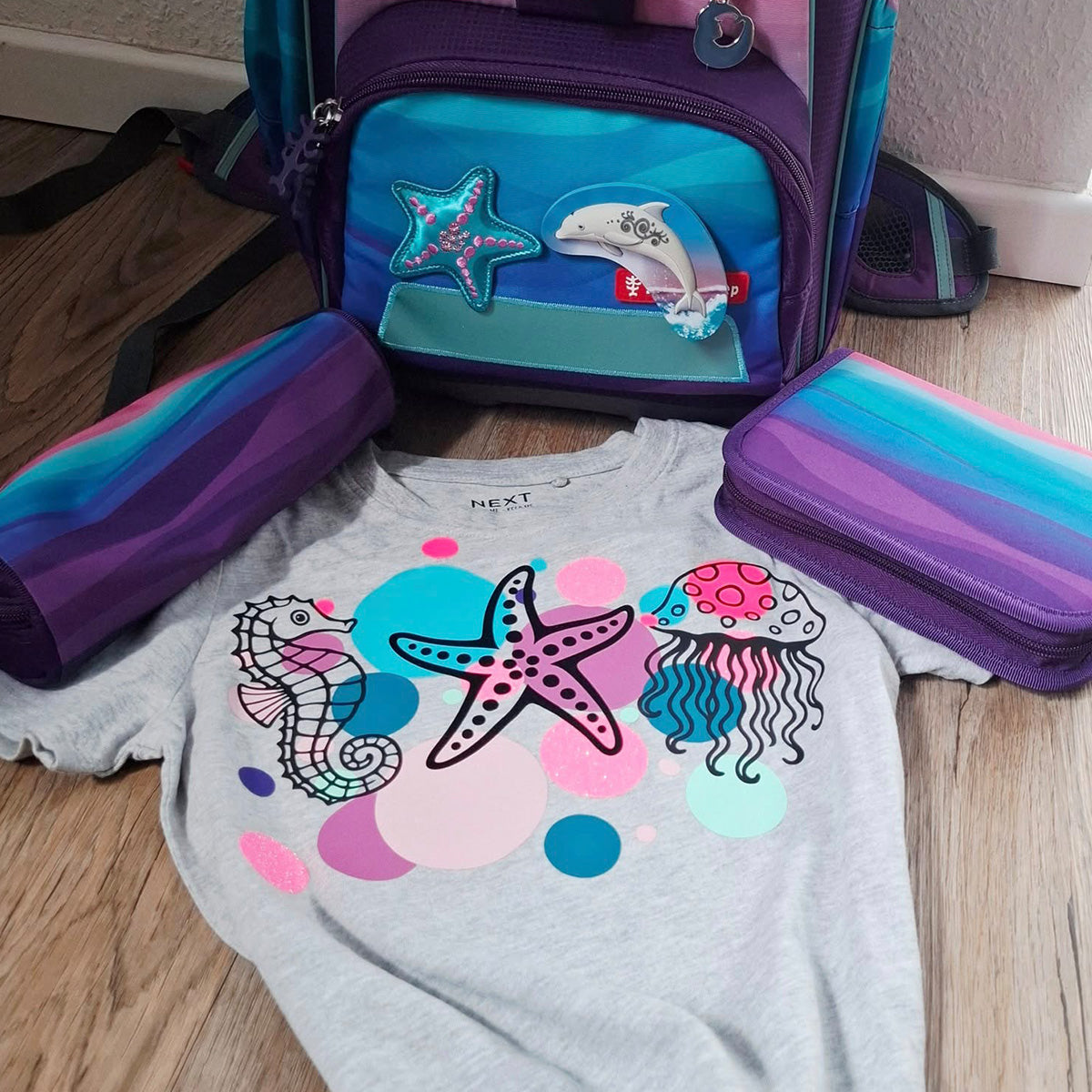 Graues Kinder-T-Shirt der Plotterdatei Sea Life mit Seepferdchen, Seestern und Qualle, daneben passender Schulranzen und Federmäppchen