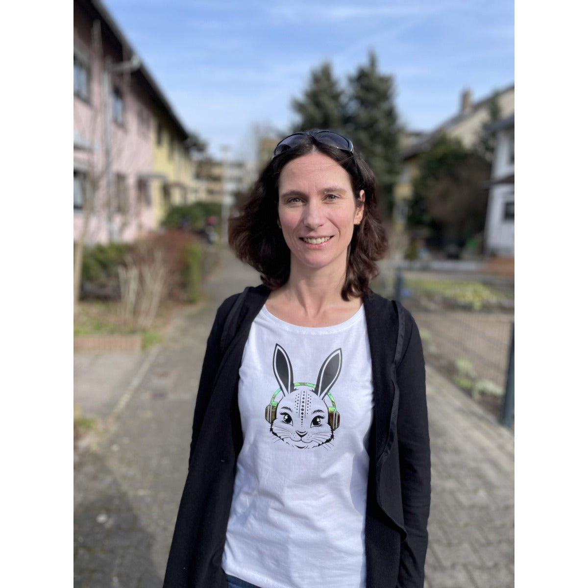 Weißes Damenshirt mit Hasenkopf und grünen Kopfhörern, draußen getragen