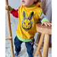 Kleinkind im gelben Shirt mit Hasenkopf und blauen Kopfhörern
