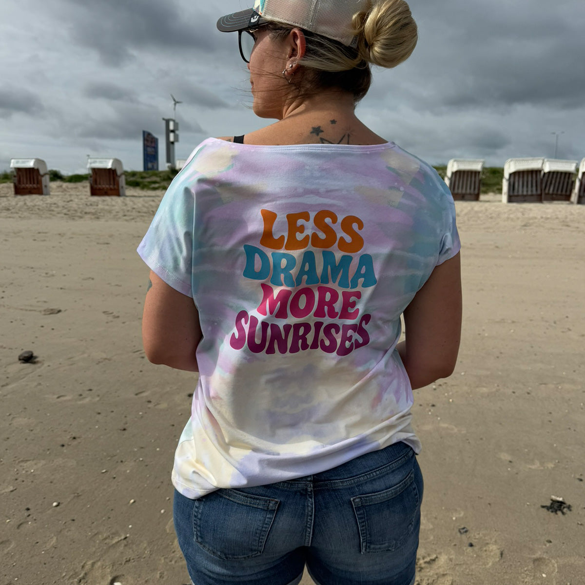 Frau am Strand von hinten im Batikshirt mit Plotterdatei „Less Drama More Sunrises"