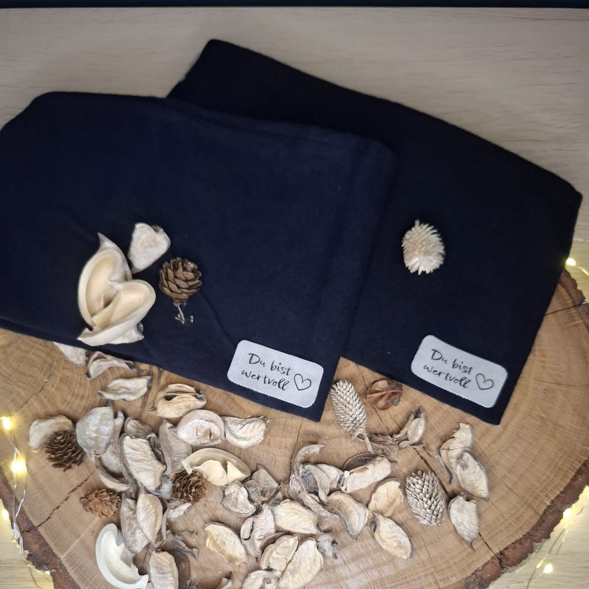 Plotterdatei Wertvolle Label – helle Label „Du bist wertvoll“ mit Herz an zwei dunkelblauen Beanies, dekoriert mit Zapfen und Trockenblüten