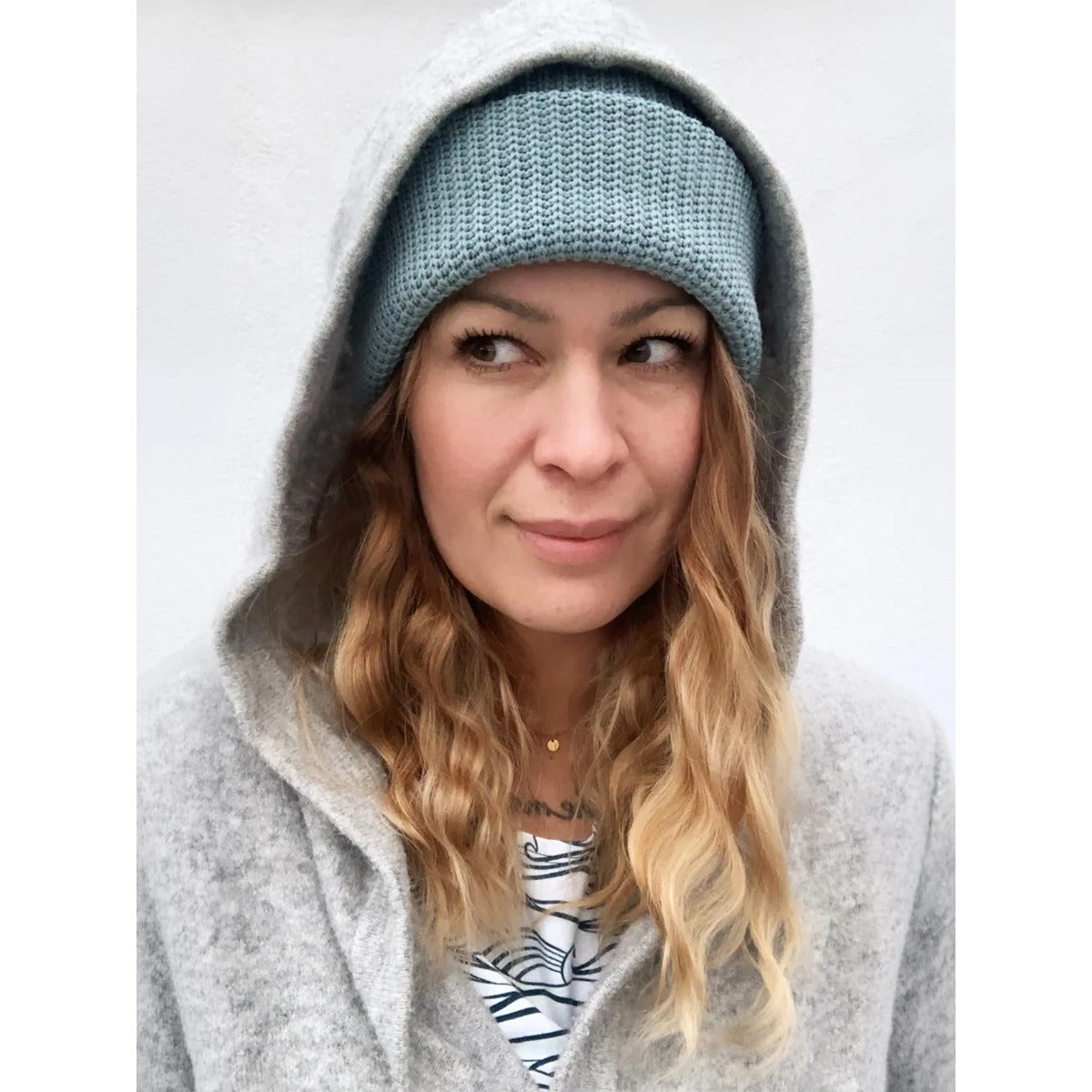 Beanie Bernie – Beanie aus dickem, hellblau-mintfarbenem Strick, getragen von einer Frau unter grauer Kapuze