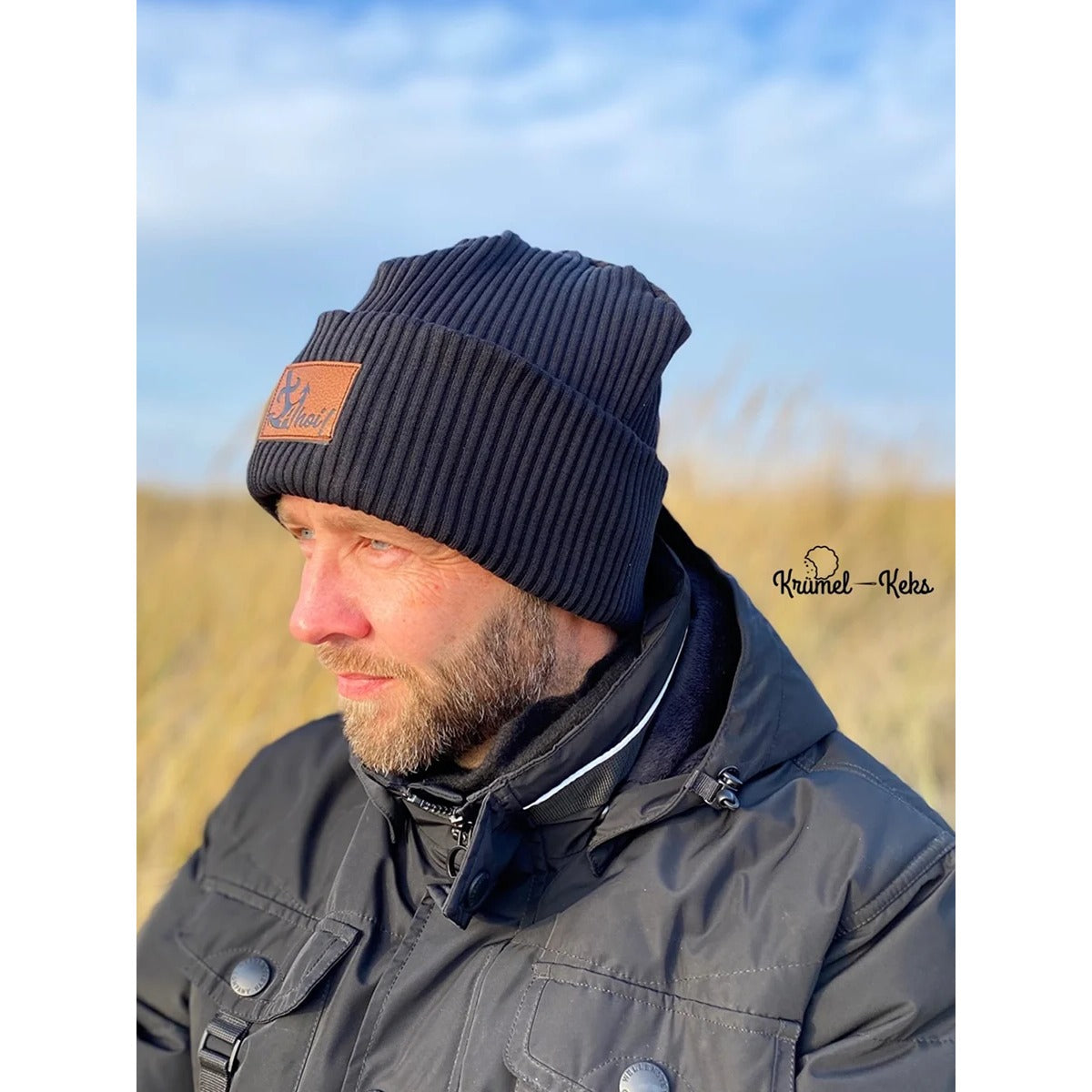 Beanie Bernie – Umschlagbeanie aus dunkelblauem Rippbündchen mit Ahoi-Kunstlederlabel, getragen von einem Mann mit Bart