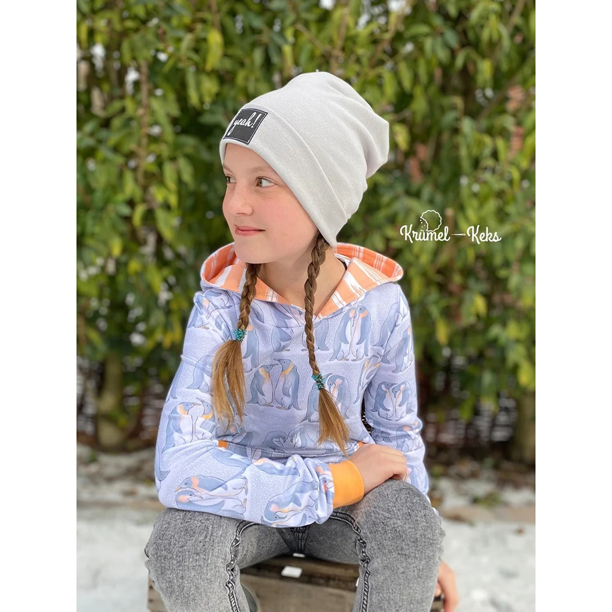 Beanie Bernie – hellgraue Umschlagbeanie mit ‚yeah!'-Label, getragen von einem Mädchen im Pinguin-Hoodie
