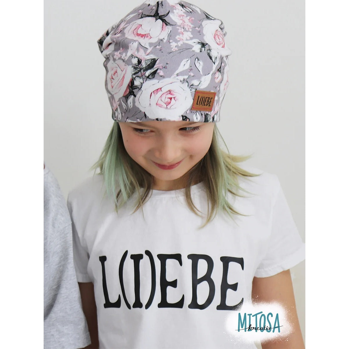 Beanie Bernie – graue Beanie ohne Umschlag mit Rosen-Print und Label, getragen von einem Mädchen im ‚Liebe'-Shirt