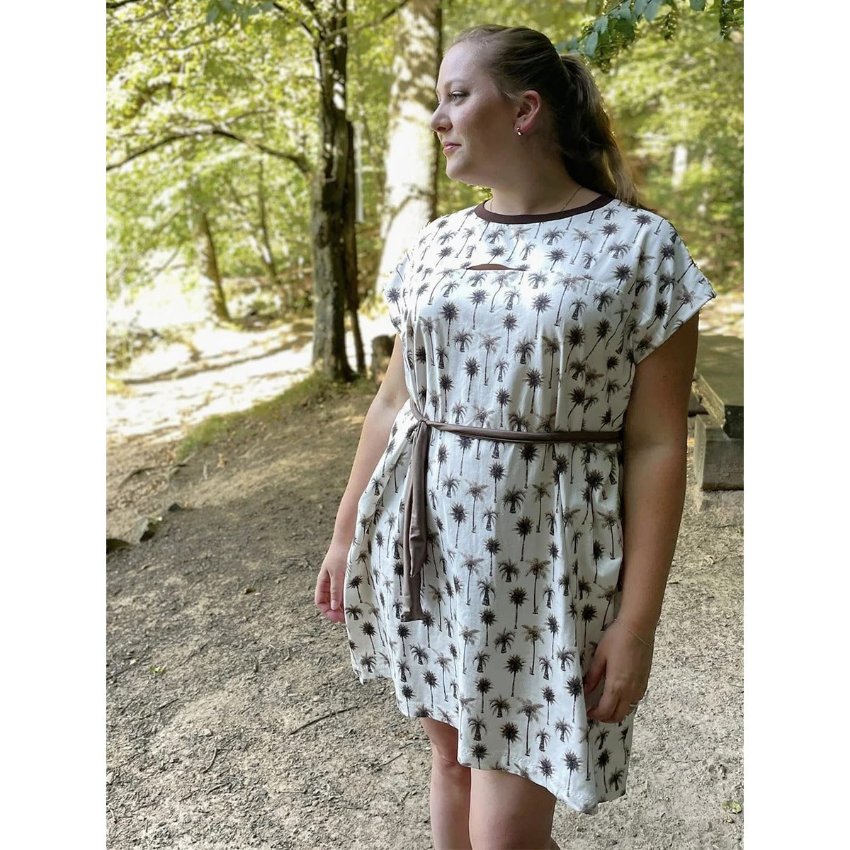 Cut Out Kleid – cremefarbenes Kleid mit Palmen-Print, braunem Halsbündchen, Cut-Out an der Brust und Bindeband an der Taille