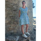 Cut Out Kleid – türkis gemustertes Kleid mit kurzen Ärmeln, Eingrifftaschen und Bindeband an der Hüfte, vor einer Steinwand