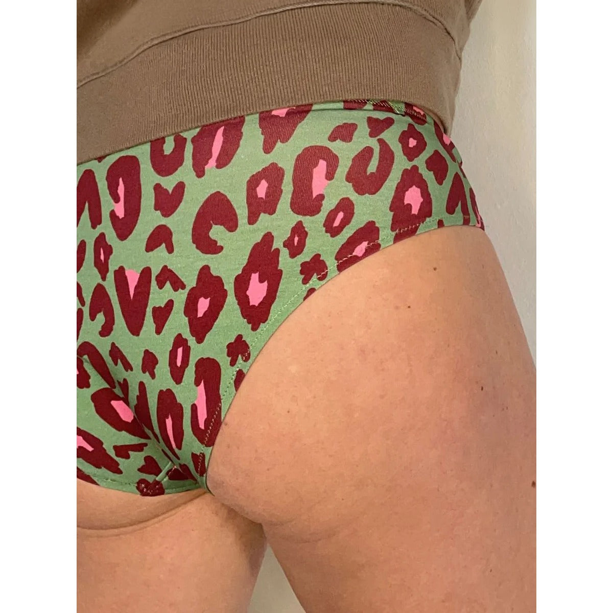 Damen Schlüppi Schnittmuster – grüne Damen-Panty mit dunkelrot-pinkem Leoparden-Print und eingeschlagenem, nicht sichtbarem Gummibund, Seitenansicht am Körper