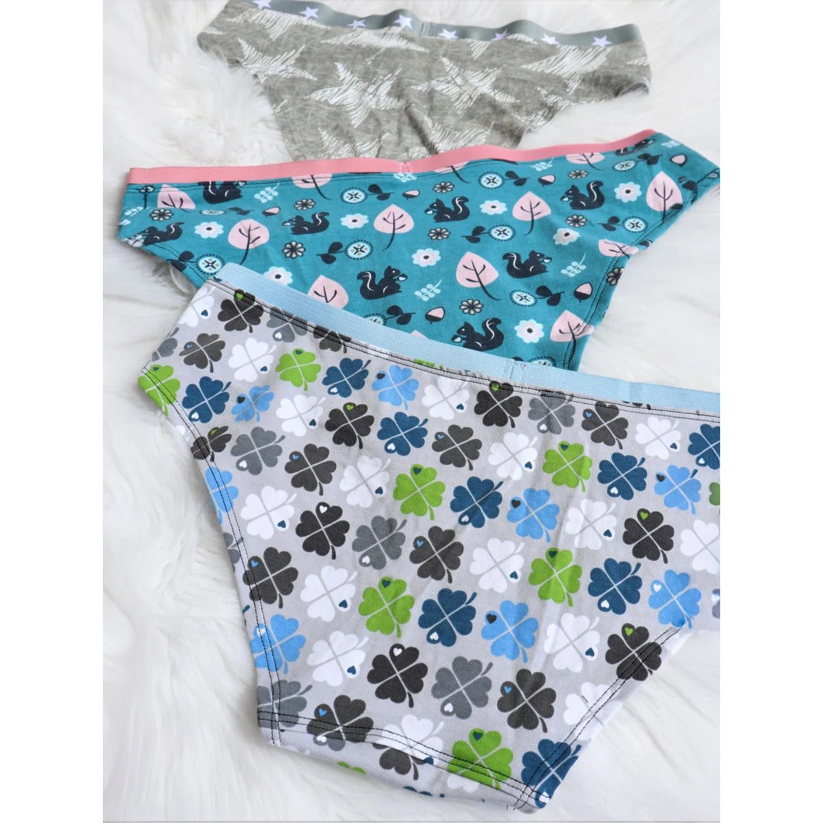 Damen Schlüppi Schnittmuster – drei Damen-Pantys mit Federn-, Eichhörnchen- und Kleeblatt-Print und sichtbar angenähten Gummibünden, Rückansicht im Flatlay