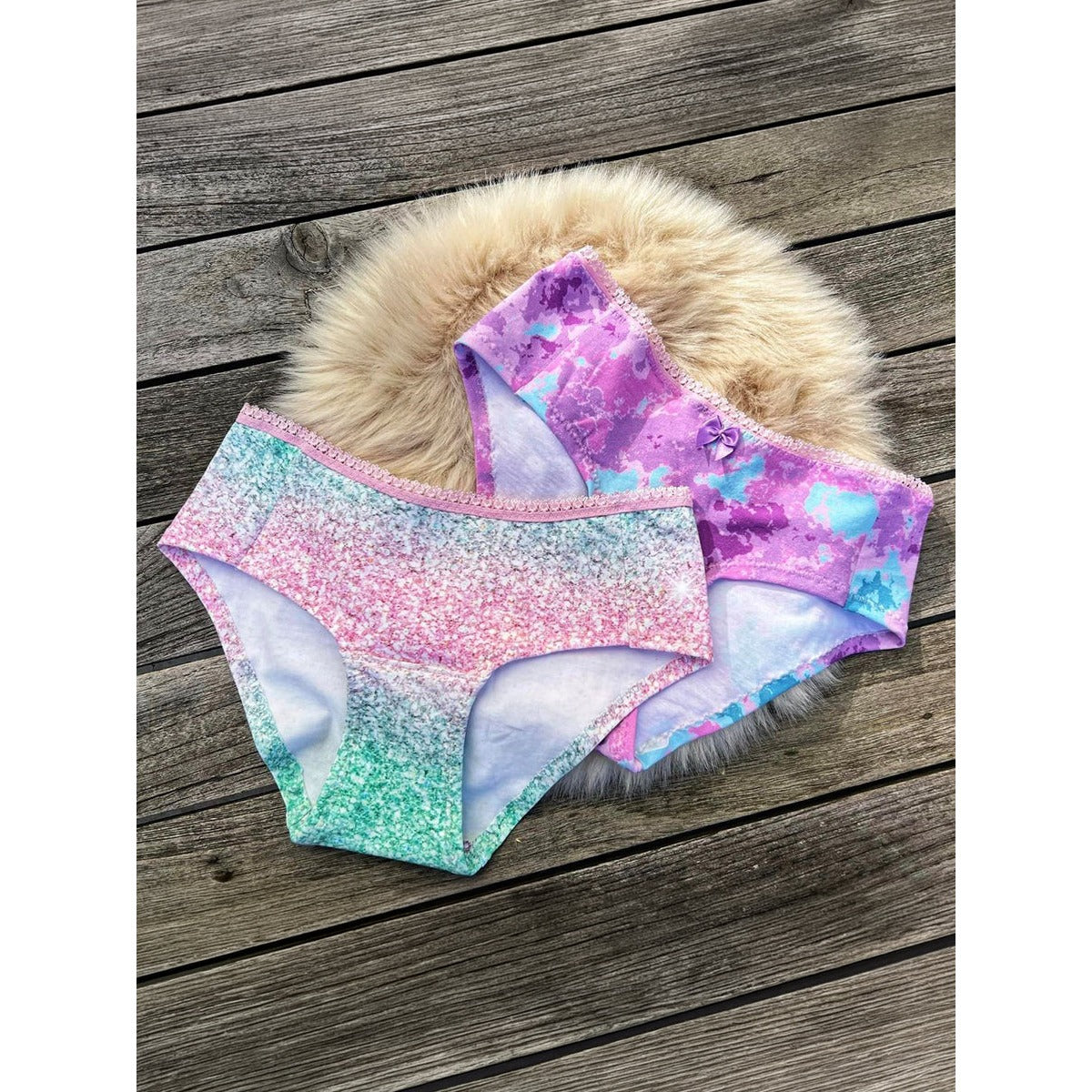 Damen Schlüppi Schnittmuster – zwei Damen-Pantys in pastelligem Glitzer-Verlauf und lila-türkisem Batik mit sichtbar angenähtem rosa Zierbund, Flatlay