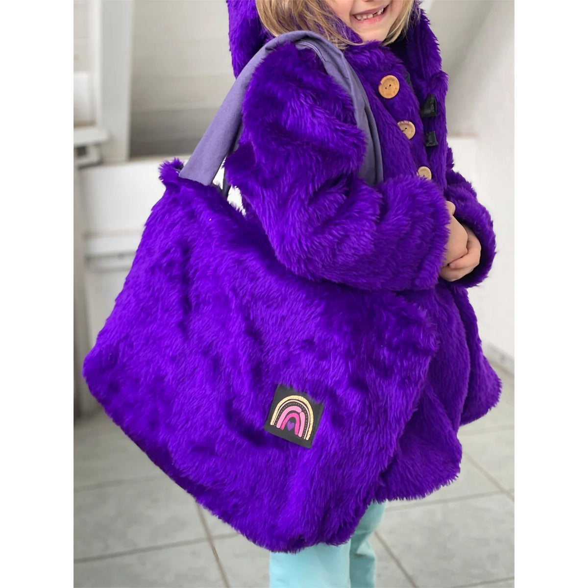 Teddy Shopper – kleine Kid Bag aus lila Plüsch mit Regenbogen-Label, von einem Kind getragen