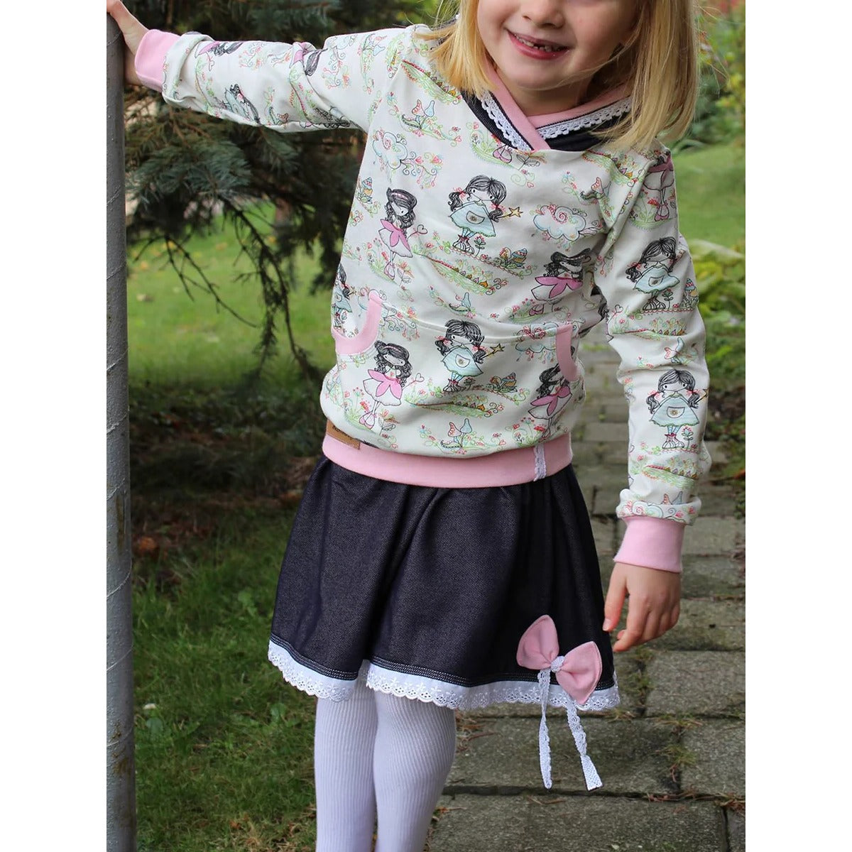 Lottchen Kinder als Hoodie aus cremefarbenem Jersey mit Mädchen-Print, rosa Bündchen und weißer Spitze am Ausschnitt, dazu Lottchen-Rock aus dunklem Jeansjersey mit Spitzenborte und rosa Schleife