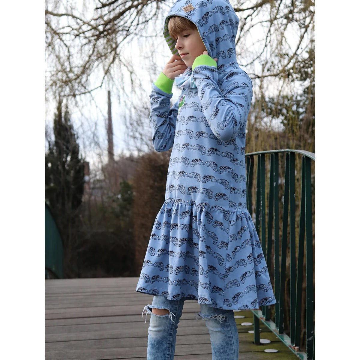 Lottchen Kinder als Hoodiekleid aus hellblauem Jersey mit Chamäleon-Print, grüne Bündchen und Kapuze mit gestreiftem Futter, angesetztes Rockteil mit Falten