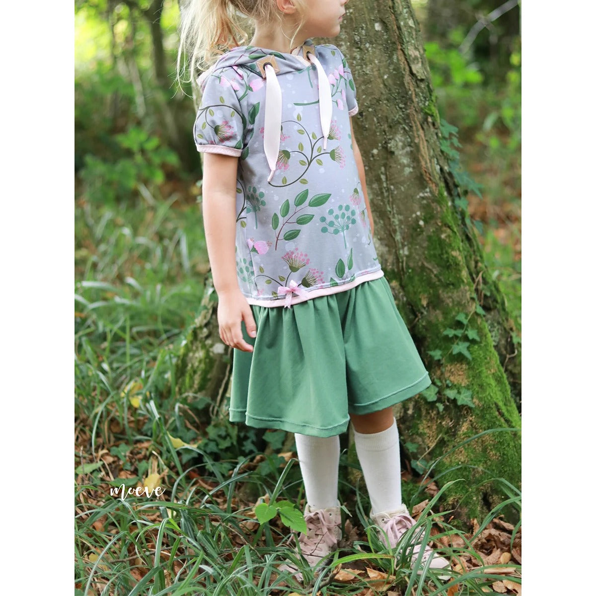 Lottchen Kinder als Hoodiekleid mit kurzen Ärmeln: graues florales Oberteil, grünes Rockteil und rosa Bündchen mit Schleife dazwischen