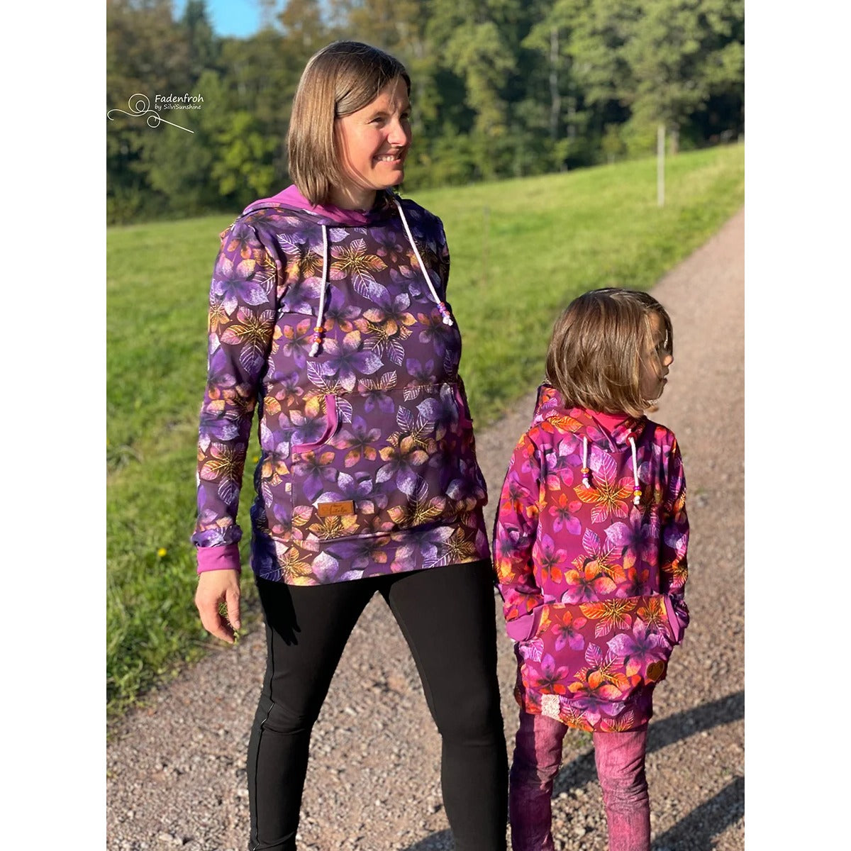 Miss Lottchen – lila-bunter Blüten-Hoodie mit Bauchtasche und Kapuze, daneben der Kinderschnitt Lottchen in der langen Version im gleichen Blätterdesign in Pink