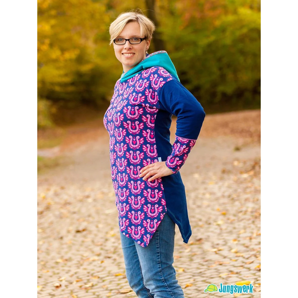 One Tip Shirt Damen als Hoodie im Stoffmix: Vorderteil mit pinkem Hufeisen-Print, blaues Rückenteil und türkis gefütterte Kapuze, Langarm, Seitenansicht mit Zipfelsaum