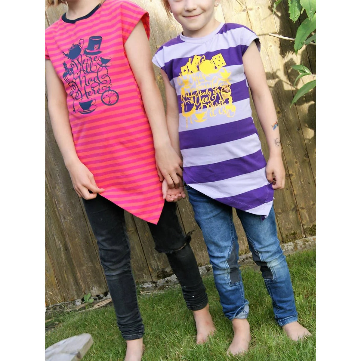 One Tip Shirt Kinder – zwei Mädchen in gestreiften Zipfelshirts mit Plotter-Print, pink-orange und lila-helllila zu Jeanshosen