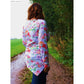 One Tip Shirt Damen als Langarmshirt aus weißem Jersey mit Aquarell-Blumen, Rückansicht mit Zipfelsaum auf einem Waldweg