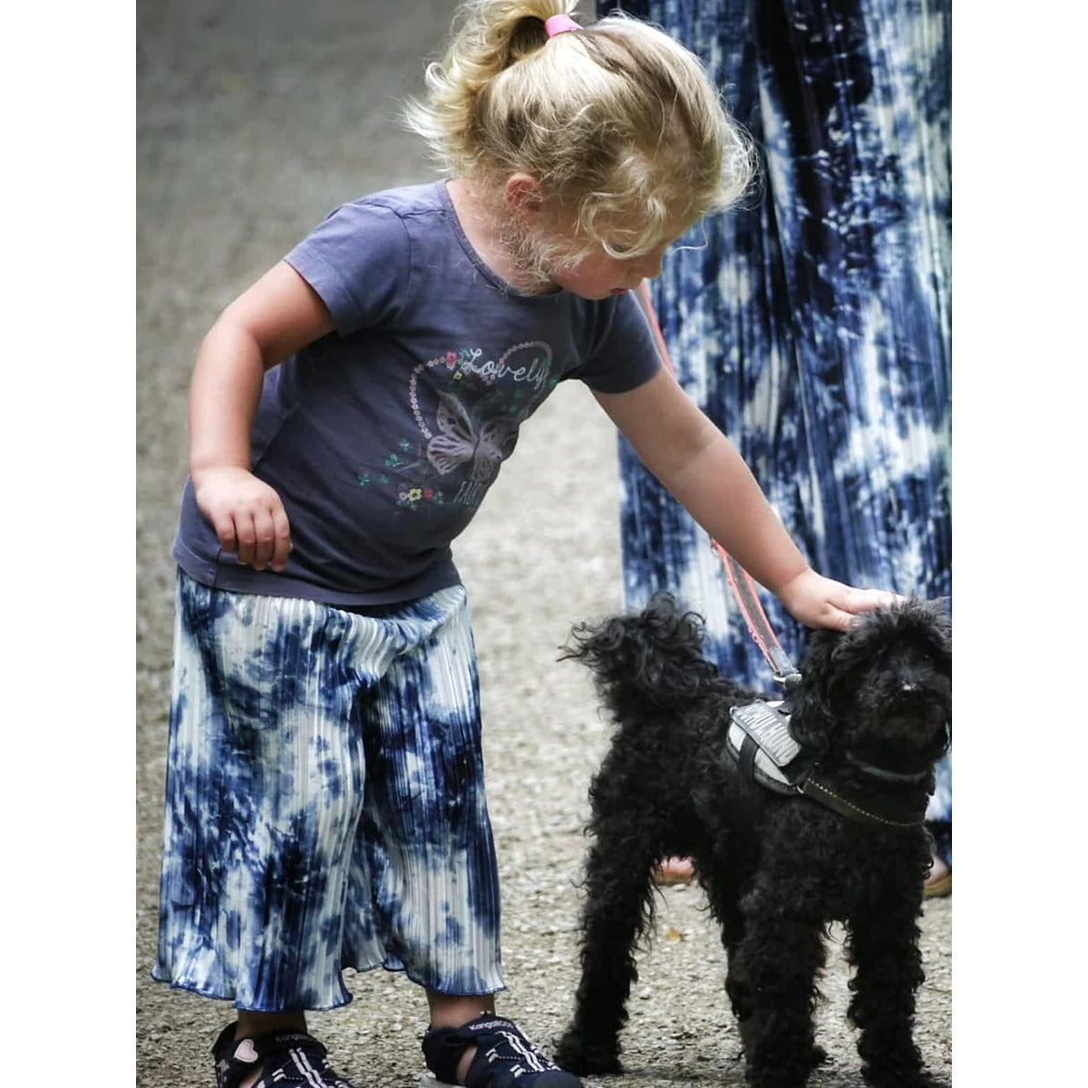 Plisseerock Mädchen – blauer Batik-Plisseerock mit Rollsaum, getragen von einem Mädchen mit Hund, dazu die Damen-Version im Partnerlook