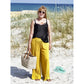 Plisseehose Damen – gelbe Plisseehose mit schwarzem Spitzentop und Korbtasche