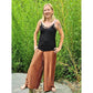 Plisseehose Damen – ockerfarbene Plisseehose mit schwarzem Top, vor Bambus