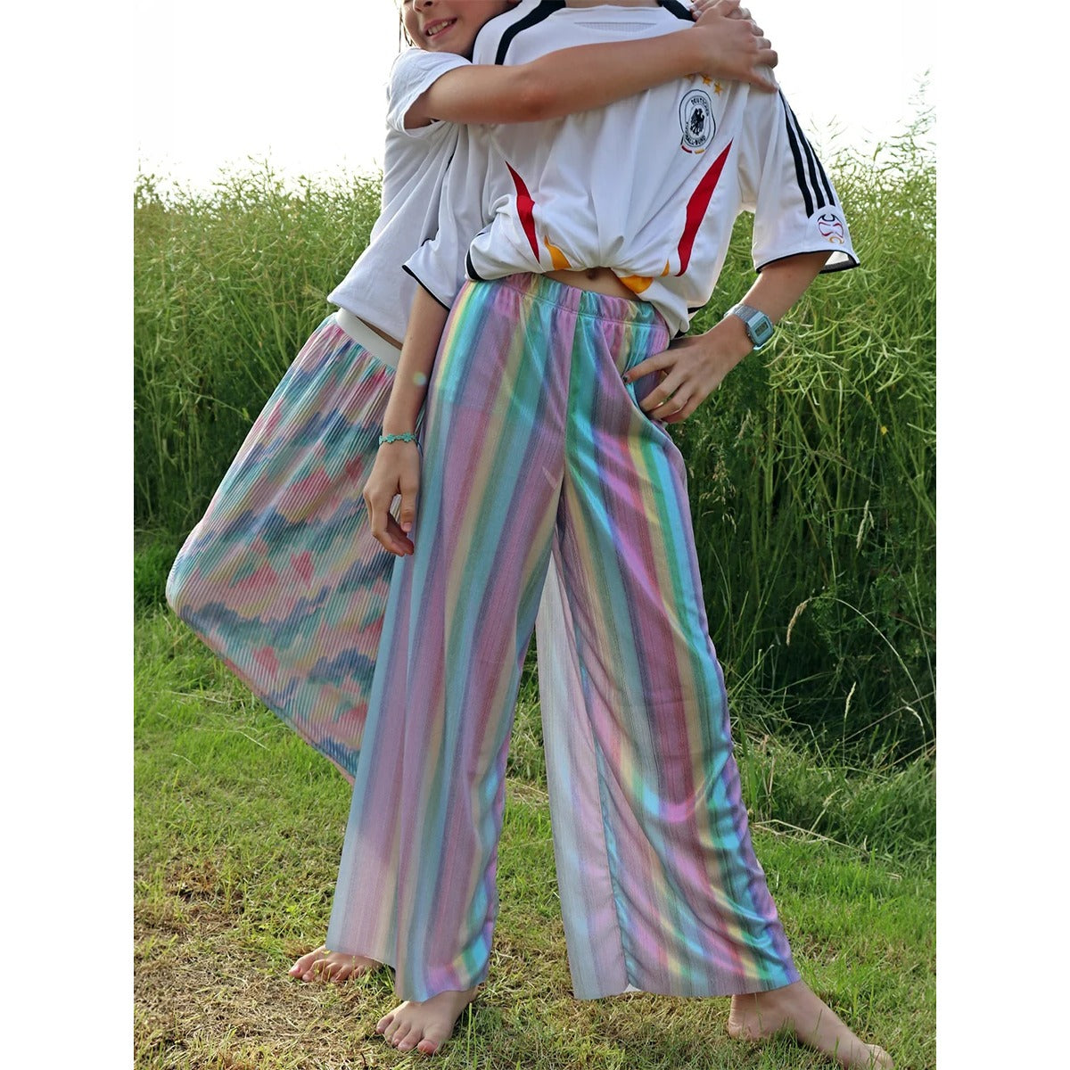Plisseehose & Plisseerock Mädchen – zwei Kinder im Partnerlook aus Regenbogenstoff, eines im Plisseerock, eines in der Plisseehose, dazu Deutschland-Trikot
