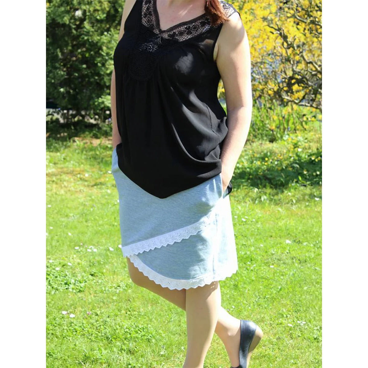 Schnittmuster Shabby Skirt Damen – hellgrauer Sweat mit weißer Lochspitze am Saum und seitlichen Eingrifftaschen, dazu schwarzes Oberteil