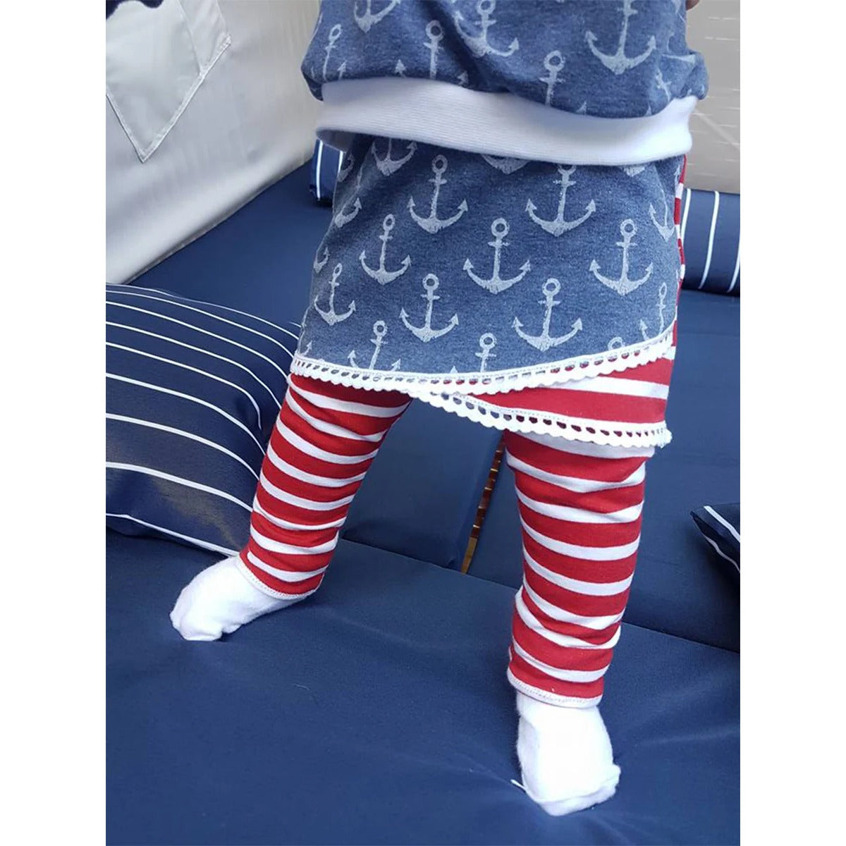 Schnittmuster Shabby Skirt Kids – jeansblauer Ankersweat im asymmetrischen Lagenlook mit weißer Häkelborte am Saum, kombiniert mit rot-weiß geringelten Leggings, Rückansicht