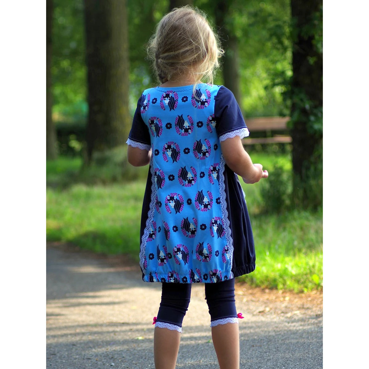 Sidecut Kleid Schnittmuster – Ballontunika in Blau und Marine mit Spitzendetails, Rückansicht eines Mädchens