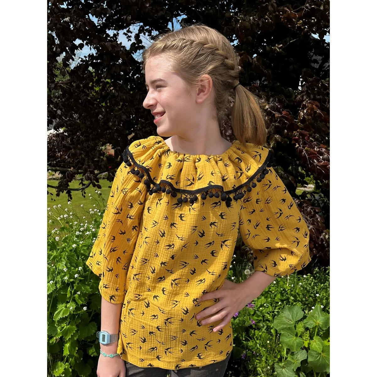 Schnittmuster Talia – senfgelbe Musselin-Bluse mit schwarzem Schwalben-Print, Volant am Ausschnitt mit schwarzer Bommelborte und 3/4-Ärmeln ohne Gummi