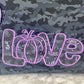 Stickdatei „Kürbis Liebe“ 20 x 30 cm – Nahaufnahme des lila LOVE-Schriftzugs auf Camouflage-Stoff