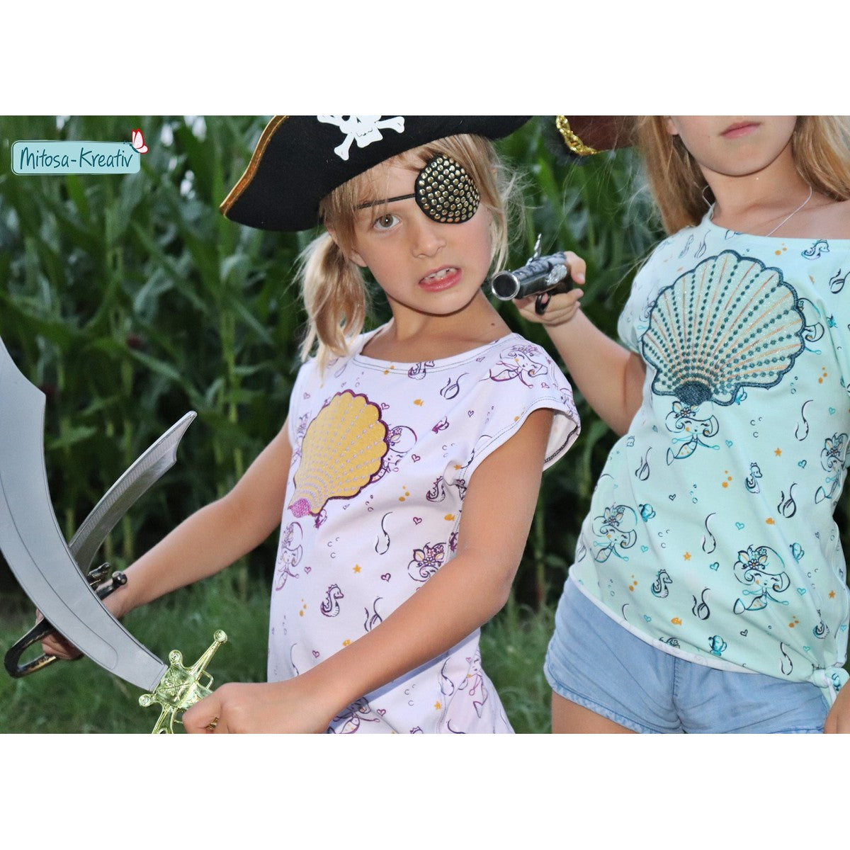 Stickdatei Muschel – zwei Piratinnen mit Säbel und Fernrohr in Shirts mit gelber und mintfarbener Applikations-Muschel