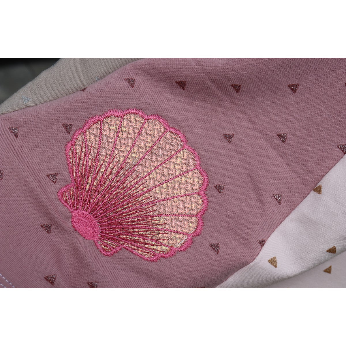 Stickdatei Muschel – pinke Folienstick-Muschel auf altrosa Stoff, Nahaufnahme