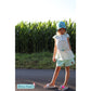 Stickdatei Muschel – Mädchen mit Sonnenhut im weißen Kleid mit großer Muschel und mintfarbenen Shorts vor einem Maisfeld