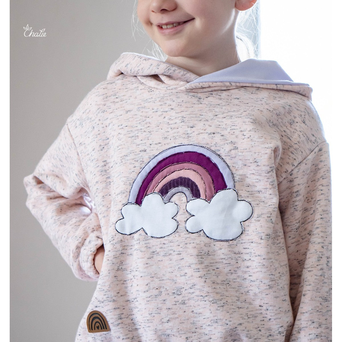 Stickdatei Regenbogen als Applikation in Beerentönen auf einem rosa Kinderhoodie