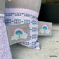 Stickdatei Regenbogen mit Glitzerwolken als Aufnäher auf einem Kissen in Rosa und Grau