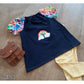 Stickdatei Regenbogen als Applikation auf einem dunkelblauen Kinderkleid mit bunten Ärmeln