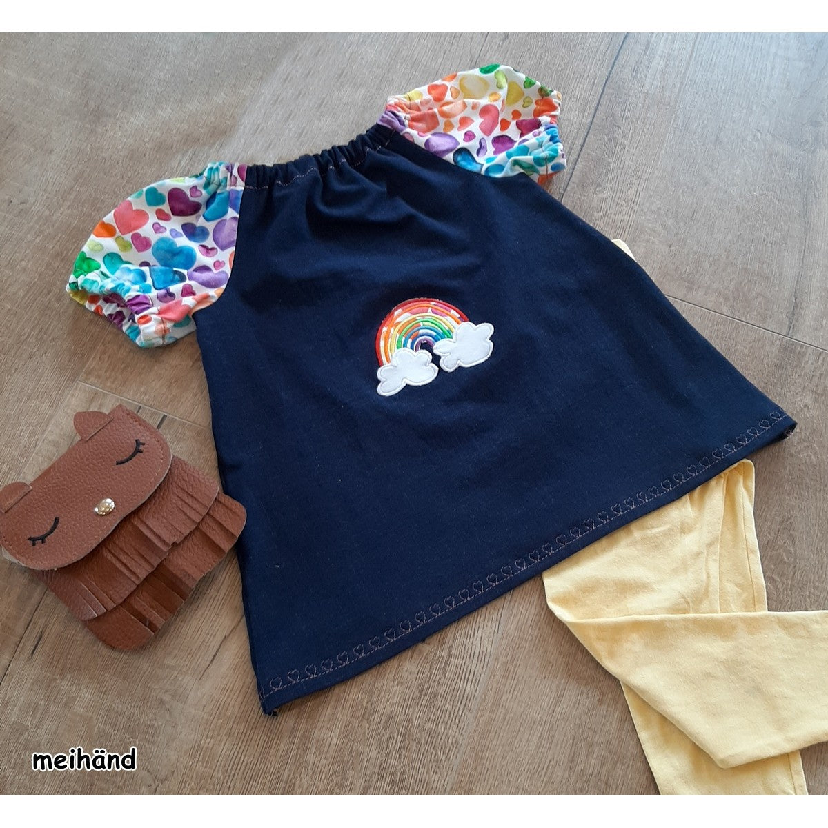Stickdatei Regenbogen als Applikation auf einem dunkelblauen Kinderkleid mit bunten Ärmeln