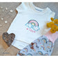 Stickdatei Regenbogen in Pastelltönen auf einem weißen Kindershirt mit gesticktem Namen