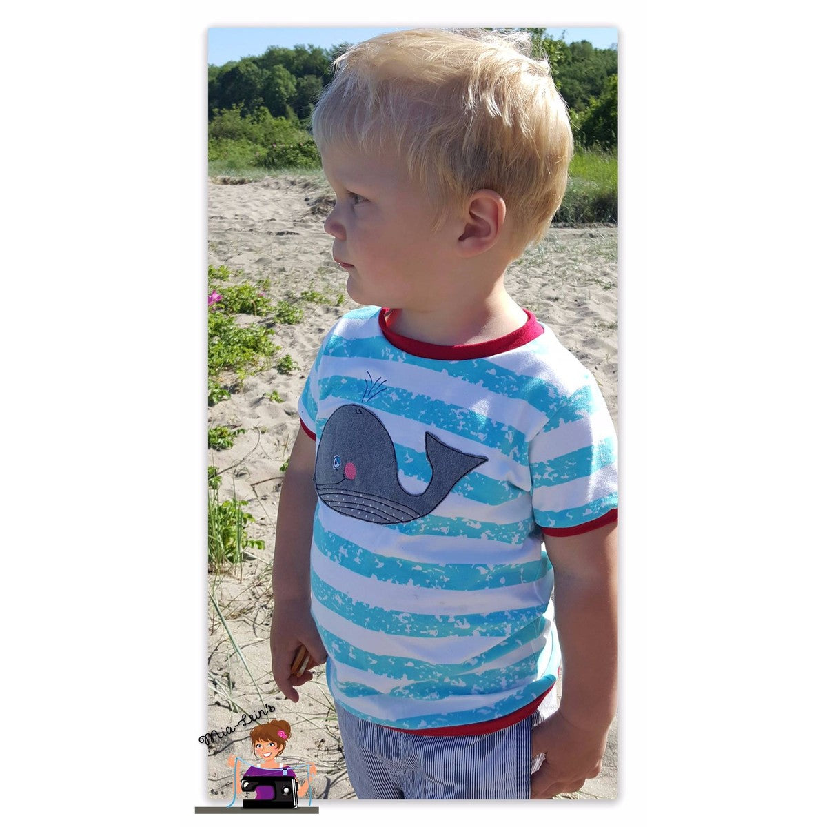 Stickdatei Walfamilie – türkis-weiß gestreiftes T-Shirt mit grauem Lotti Wal als Applikation, getragen am Strand